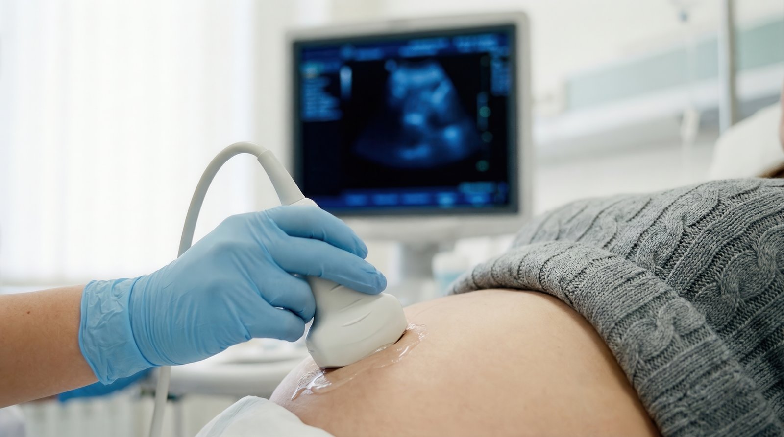 doctor performing an ultrasound scan on a pregnant womans belly